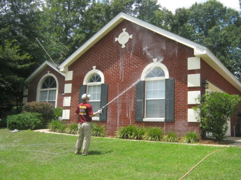 Man washing red brick home.