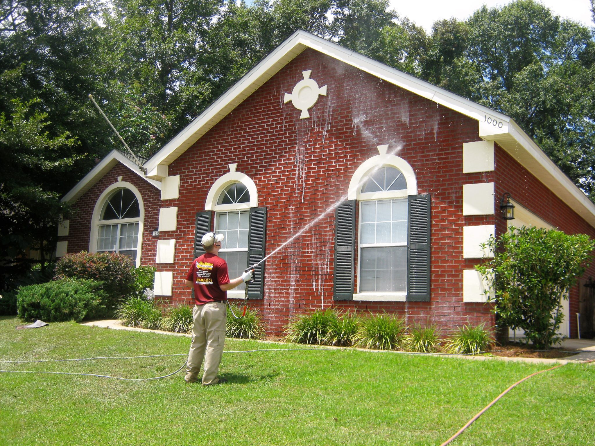 Man soft washing red brick house in Tallahassee