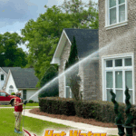 A technician from Hot Water Pressure Washing carefully soft washes the exterior of a home in Bradfordville, FL, using a low-pressure spray to apply cleaning solution.