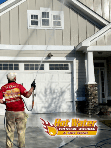 A photo of Nick Loomis, the owner of Hot Water Pressure Washing & Soft Wash, soft washing a Tallahassee home with Hardie board siding.