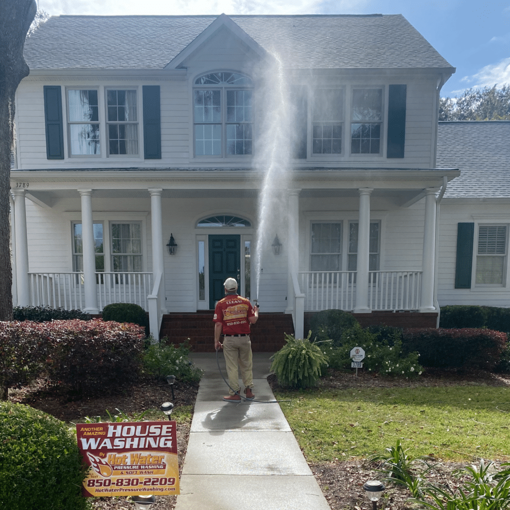 A photo of Hot Water Pressure Washing & Soft Wash cleaning a home in the Southwood community, Tallahassee, Florida. The company's logo is visible on a yard sign.