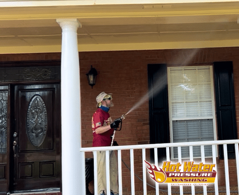 A technician soft washing a large wrap-around porch in Live Oak Plantation to remove seasonal pollen and bug spots for a repeat customer in Tallahassee, FL.
