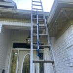 Our Gutter Hawg tool hooked onto an extension ladder, ready to make cleaning these house gutters quick and easy.