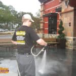 A 2014 photo of Nick Loomis pressure washing the concrete entrance and storefront of the BJ's Brewhouse restaurant in Tallahassee, Florida.