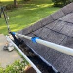 The hook feature of the Gutter Hawg tool easily pulling trapped leaves and debris from underneath a metal gutter hangar.