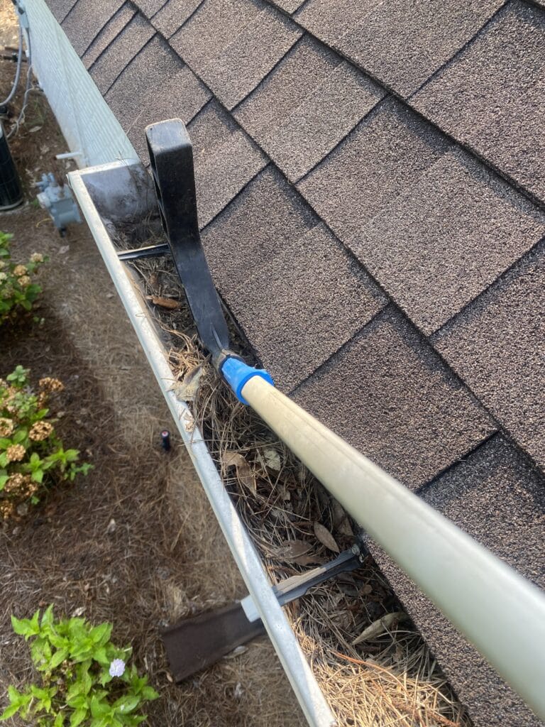 From my view on the ladder, I'm using the Gutter Hawg's scoop to pull heavy gutter debris towards me for easy removal.