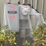 A generator switch panel properly covered with a plastic tarp and sealed with waterproof tape by Hot Water Pressure Washing, demonstrating a crucial safety step before a soft wash.