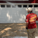 A technician rinsing a red house during a professional Soft Wash House Washing service in the Lake Jackson area of Tallahassee, Florida.