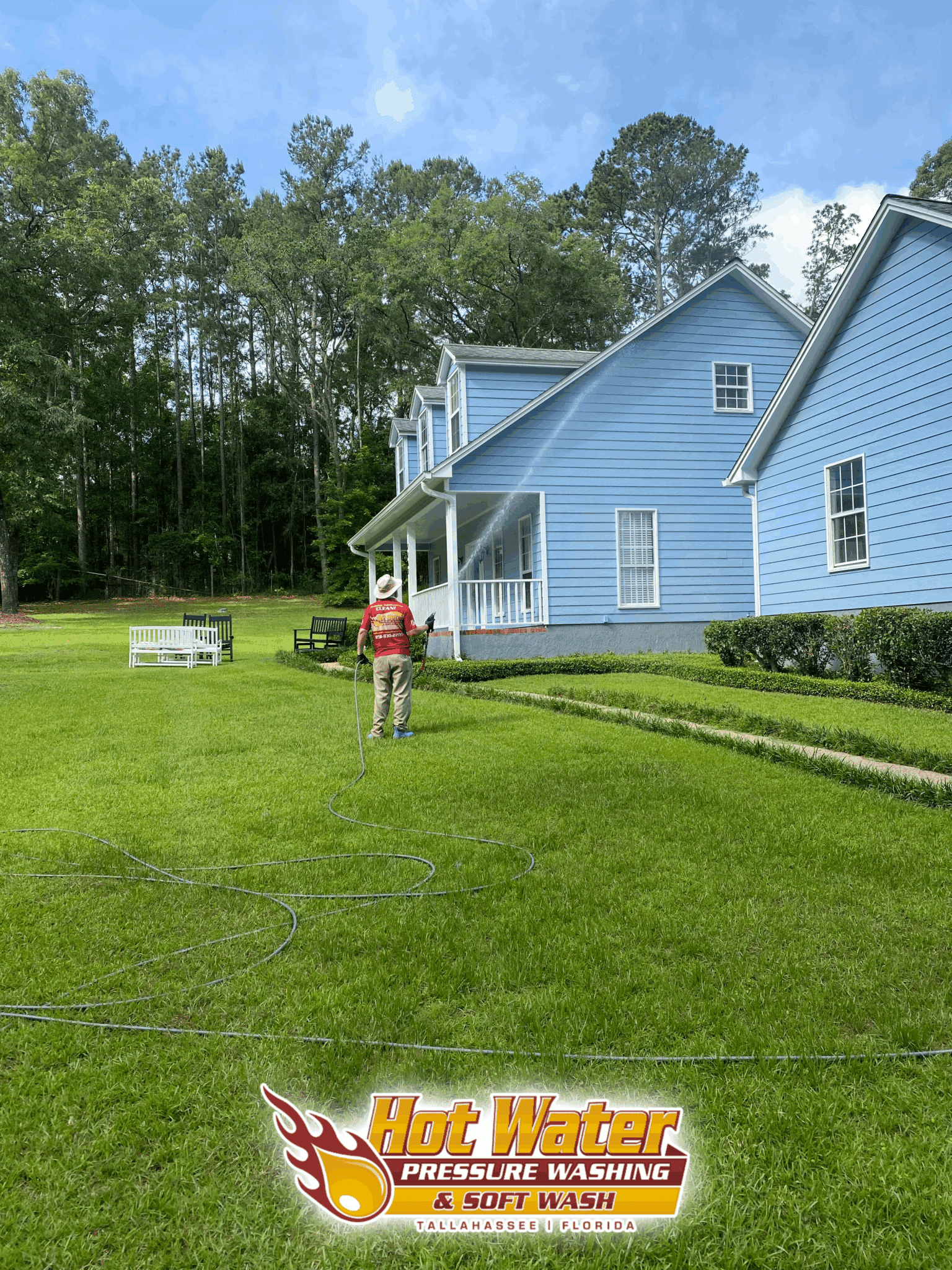 A technician from Hot Water Pressure Washing performing a Soft Wash House Washing service on a large blue home in the Killearn Lakes neighborhood of Tallahassee, FL.