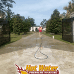 The final rinse phase of a large driveway cleaning at a gated residential property in Tallahassee, FL, revealing a spotless concrete surface.