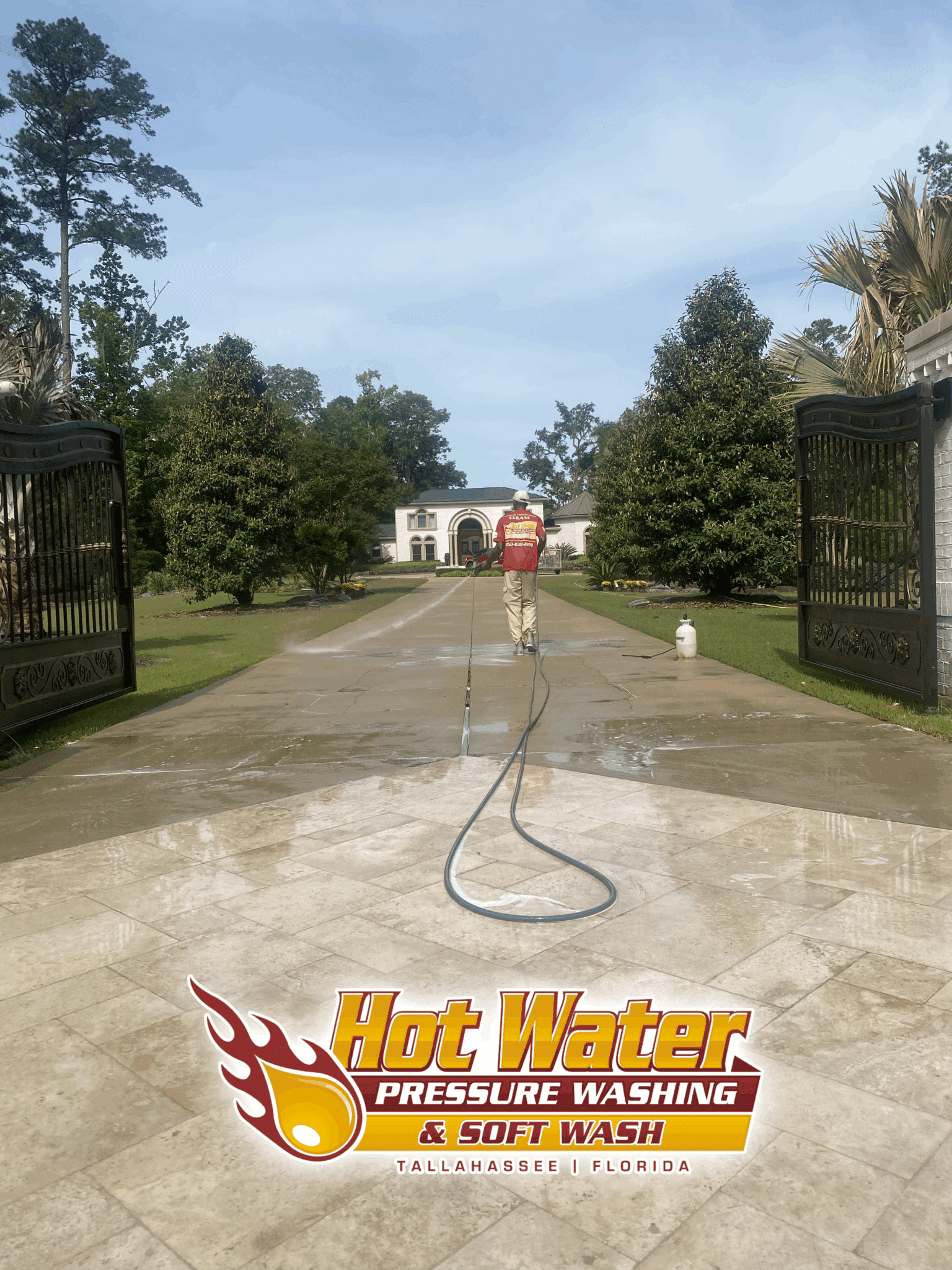 The final rinse phase of a large driveway cleaning at a gated residential property in Tallahassee, FL, revealing a spotless concrete surface.