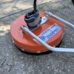 A Whisper Wash surface cleaner with ankle weights strapped to the housing to prevent lift during high GPM operation.