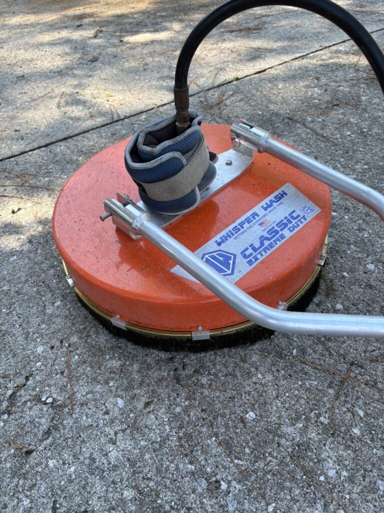 A Whisper Wash surface cleaner with ankle weights strapped to the housing to prevent lift during high GPM operation.