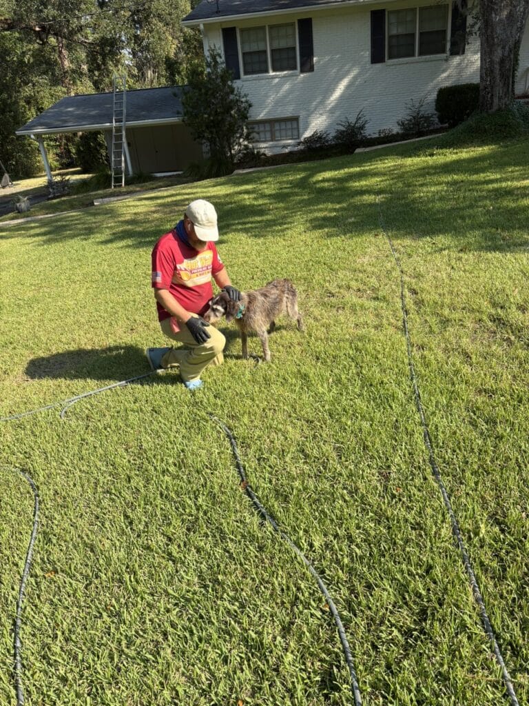 Nick Loomis, owner of Hot Water Pressure Washing, petting a customer's dog at a safe distance to demonstrate pet safety during a house wash.