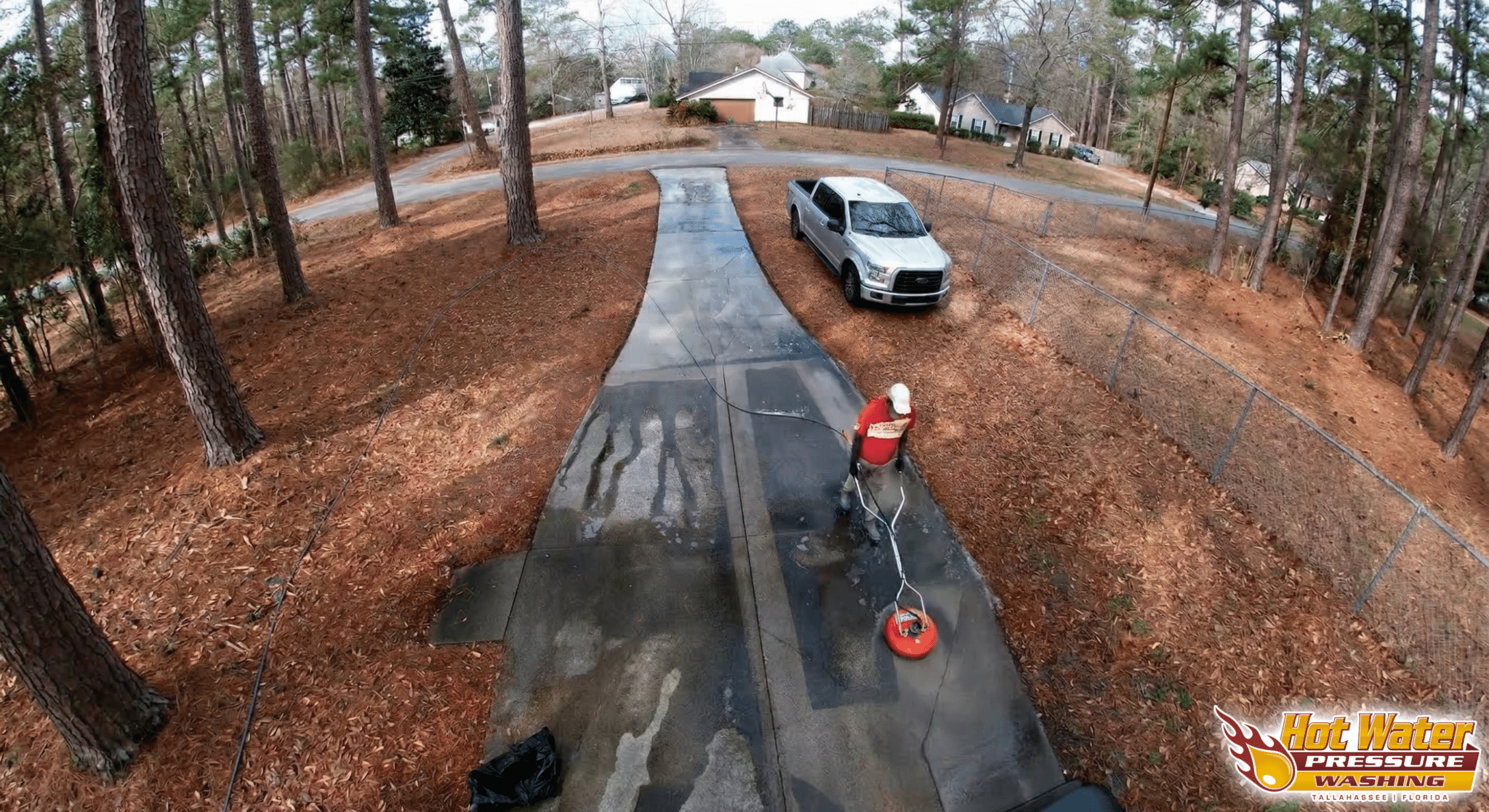 Overhead shot of a technician restoring a dirty concrete driveway in the Killearn Acres neighborhood of Tallahassee, Florida, using professional pressure washing equipment.