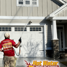 A photo of Nick Loomis, the owner of Hot Water Pressure Washing soft washing a Tallahassee home with Hardie board siding