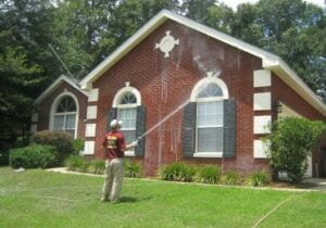 Man washing red brick home.