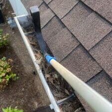 From my view on the ladder, I'm using the Gutter Hawg's scoop to pull heavy gutter debris towards me for easy removal.