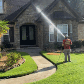 A Hot Water Pressure Washing technician carefully applying a low-pressure soft wash solution to the siding of a home in Tallahassee, Florida.