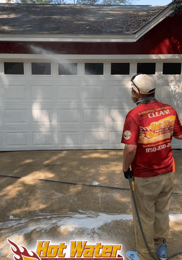 A technician rinsing a red house during a professional Soft Wash House Washing service in the Lake Jackson area of Tallahassee, Florida.