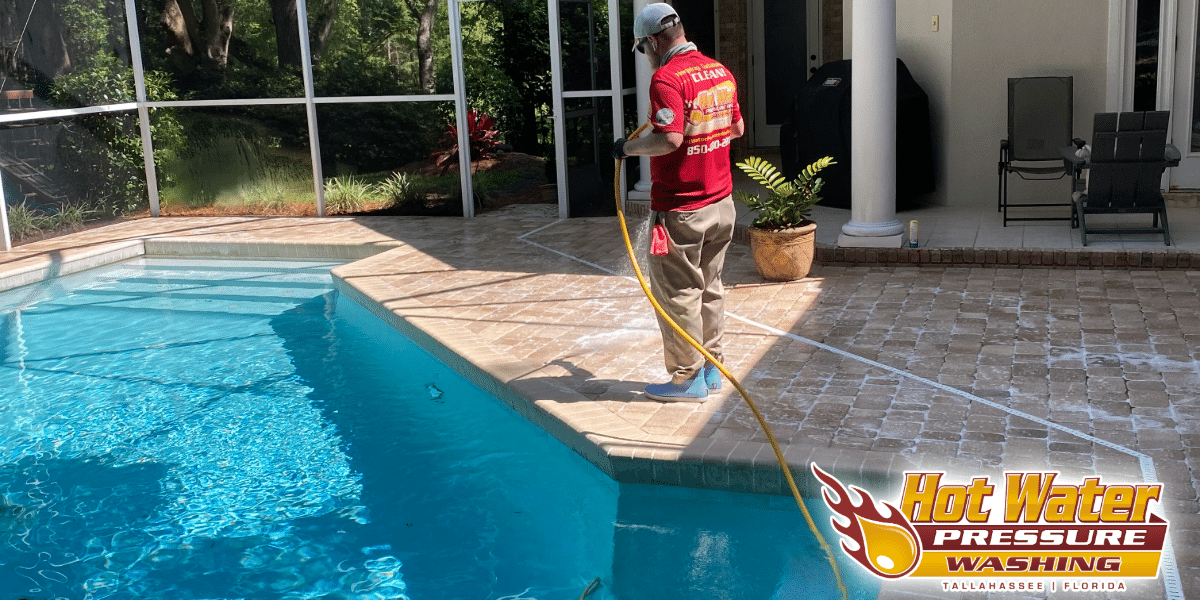 A Hot Water Pressure Washing professional safely soft washing a brick paver pool deck under a screen enclosure in the Baker Place neighborhood of Tallahassee, Florida.